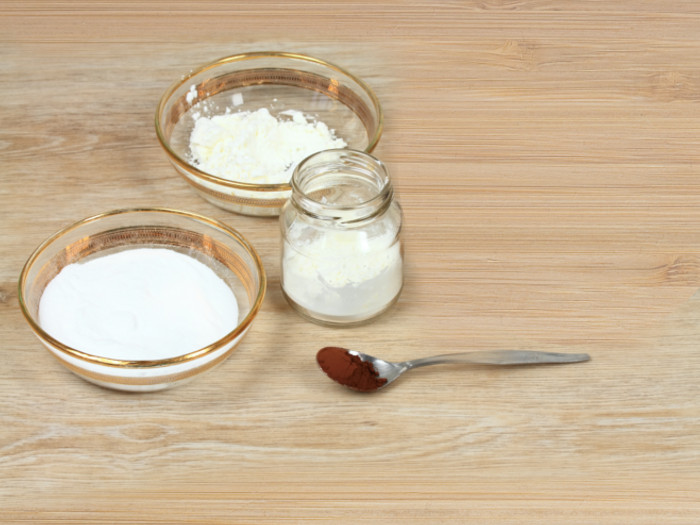 Two bowls and one bottle containing white powder and a spoon containing brown-colored powder.