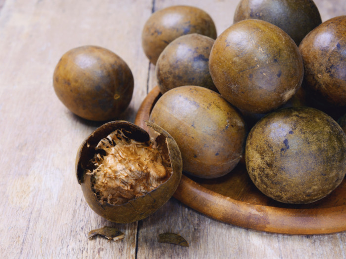 Half-peeled monk fruit and full fruits on a flat wooden plate