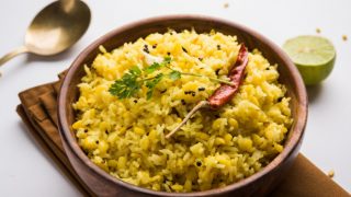Spiced rice with coriander, mustard seeds, and red chili in a wooden bowl
