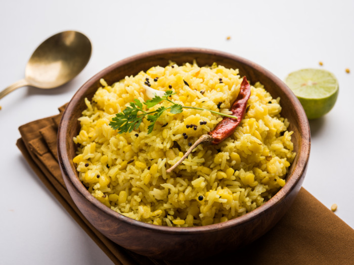 Spiced rice with coriander, mustard seeds, and red chili in a wooden bowl