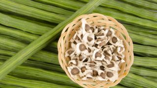 Whole moringa or drumsticks with moringa seeds in a cane basket