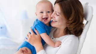 A happy mother hugging a smiling baby