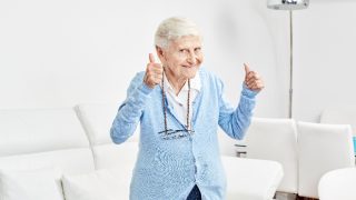 An older woman holds the thumbs up full of happiness and excitement