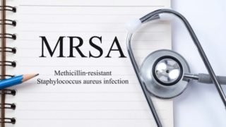 A white board saying MRSA with a pencil and a stethoscope placed alongside.
