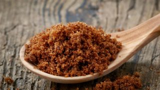Muscovado sugar in a spoon on a wooden surface