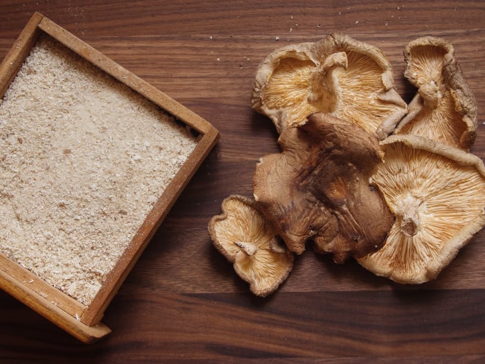 A flat lay picture of dried shiitake mushroom and its powder kept atop a table