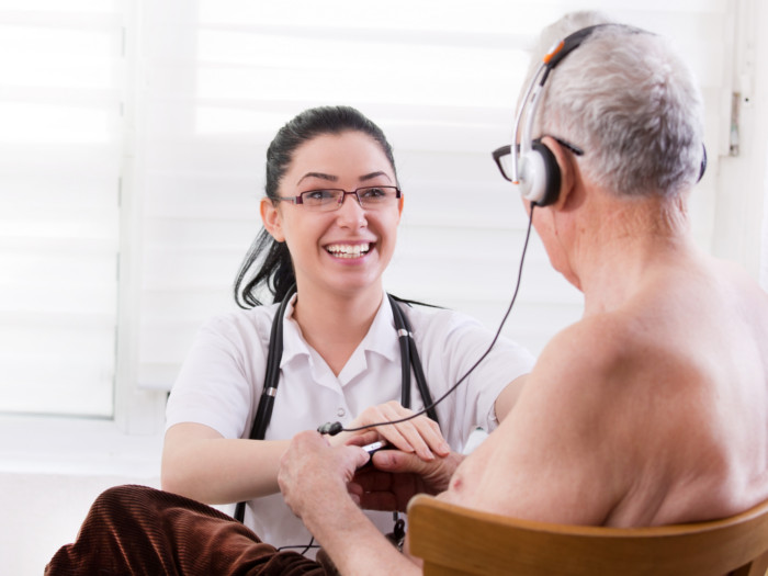 A woman doctor with an older adult wearing headphones