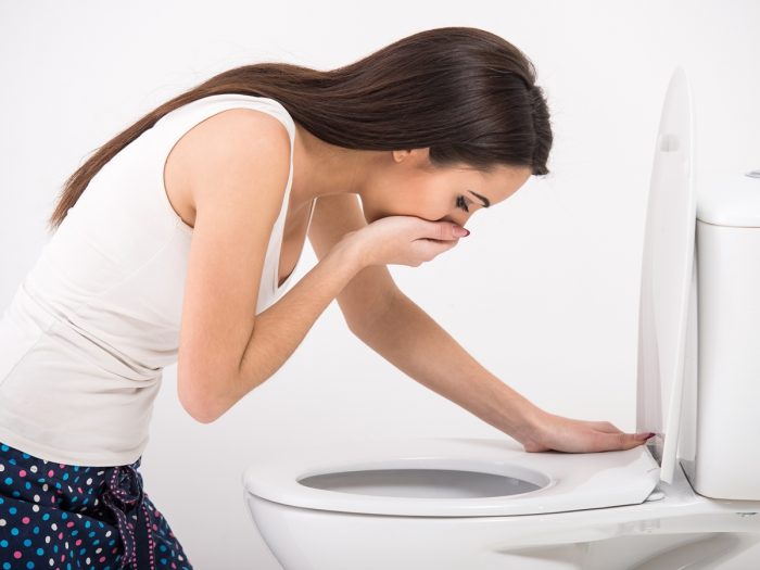 A young woman trying to vomit in a commode