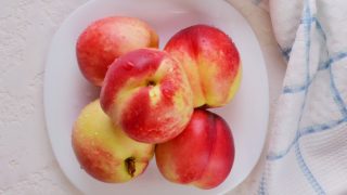 Nectarines kept in a white dish in a white background