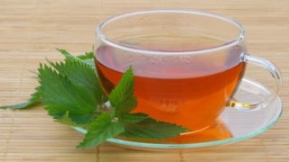 A cup of nettle tea with fresh nettle leaves