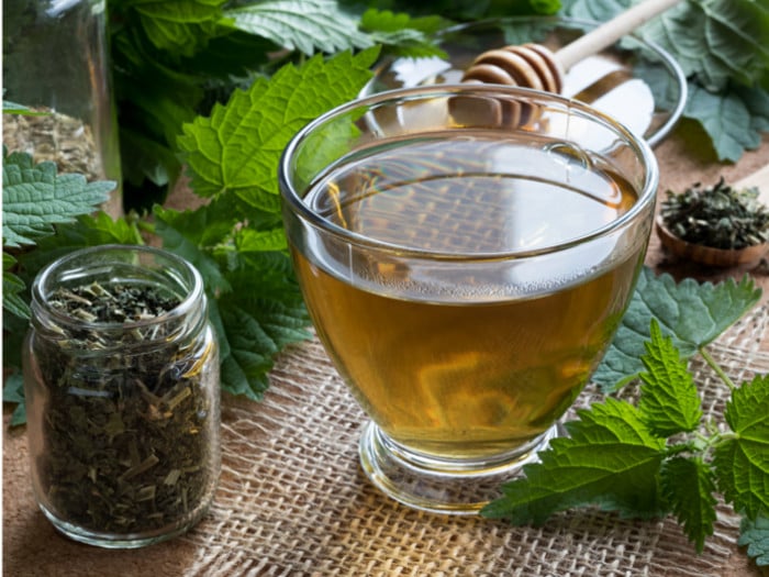 A cup of nettle tea and a bottle of tea leaves on a table