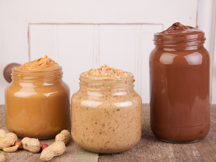Different kinds of homemade nut butter on a wooden table