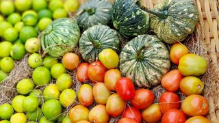 Tomatoes, pumpkins, and citrus fruits on a hay stack basket