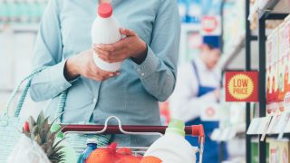 A woman doing grocery shopping at the supermarket and reading food labels