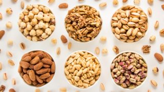 Different varieties of nuts in bowls like almonds and pistachios