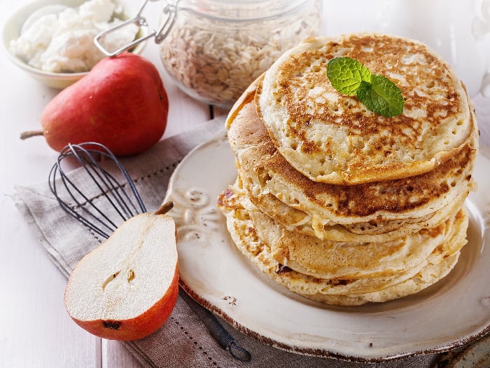 Stack of healthy low carbs oat pancakes over white wooden background