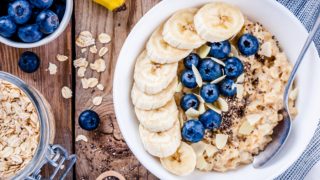 Oatmeal bowl with fresh blueberries, sliced bananas, chia seeds, and milk
