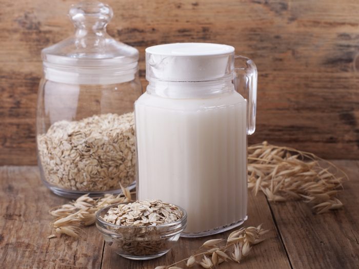 A jar filled with oat milk kept next to a jar of oats