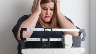 A worried overweight woman on a weighing scale