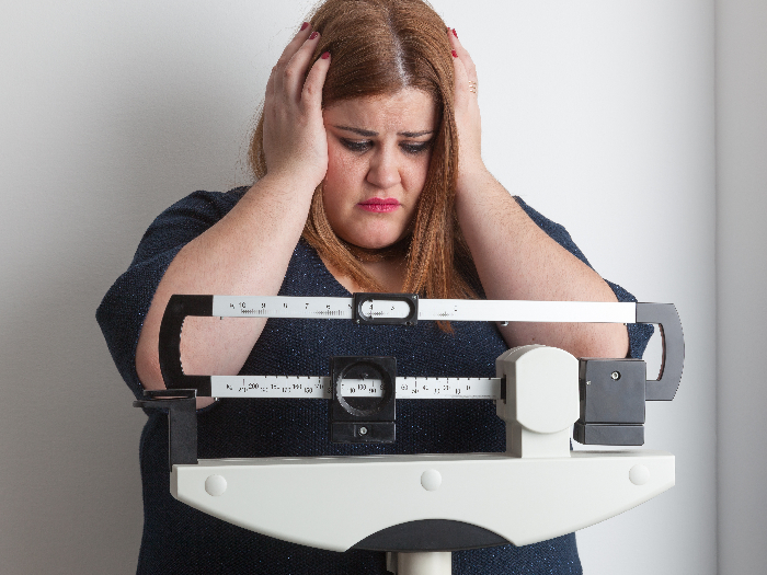 A worried overweight woman on a weighing scale