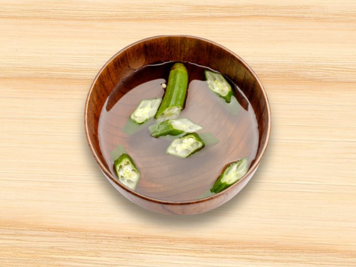 Okra pieces in water in a wooden bowl