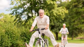 Happy senior couple riding bicycles at summer park