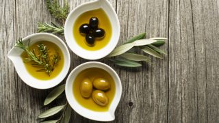 Green and black olives in a white bowl on a wooden table