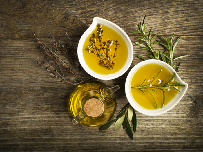Olive oil infused with herbs such as rosemary and sage in a bottle and small dishes