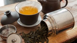 A cup of oolong tea with a teapot and oolong tea leaves on a wooden table