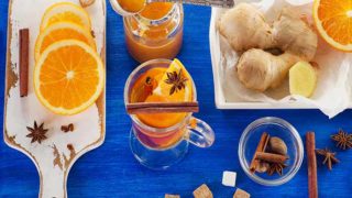 A flat lay picture of oranges, spices, sugar, and tea - all the necessary ingredients required to make a cup of orange tea