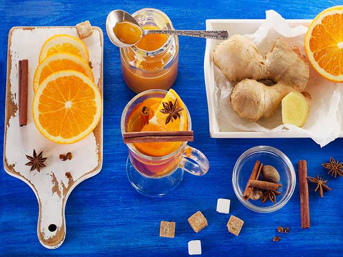 A flat lay picture of oranges, spices, sugar, and tea - all the necessary ingredients required to make a cup of orange tea