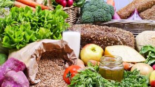 Fresh fruits, vegetables, grains, bread, a glass of milk, cheese and a jar of herbed oil