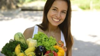Smiling woman holding a bag of fruits and vegetables