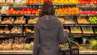 A woman standing in front of shelves of vegetables in a store.