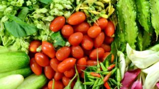 Close-up of different vegetables: tomatoes, cucumbers, chilies, and green leafy vegetables.