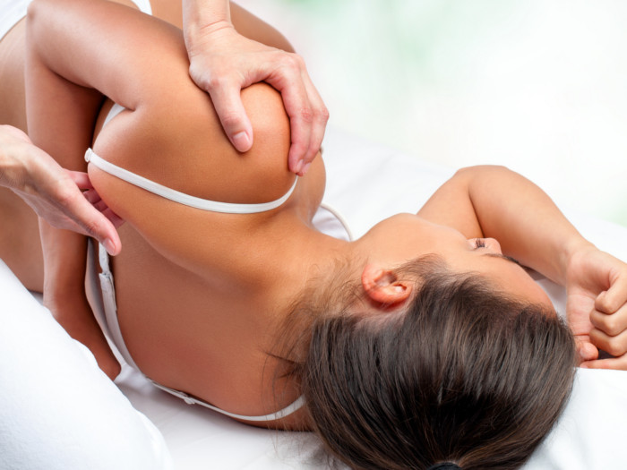 Close-up top view of osteopath doing healing treatment on female shoulder blade