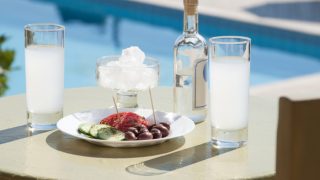 Two glasses of ouzo served with salad and nuts on a table near the swimming pool