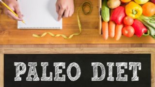 A notebook, measuring tape, and some vegetables placed above a label of 'paleo diet'