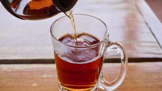 Pouring Palo azul or kidneywood tea in a glass on a wooden table