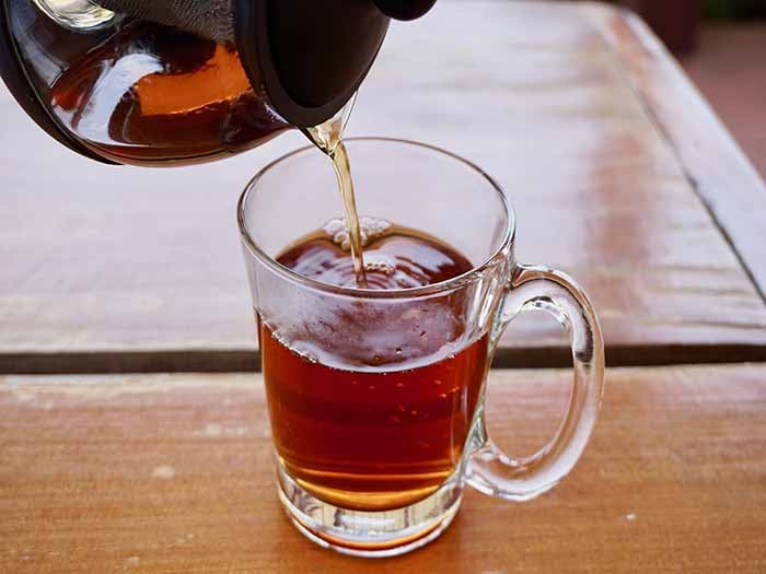 Pouring Palo azul or kidneywood tea in a glass on a wooden table