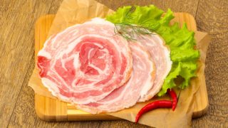 Pancetta on a parchment paper with lettuce and red chilies