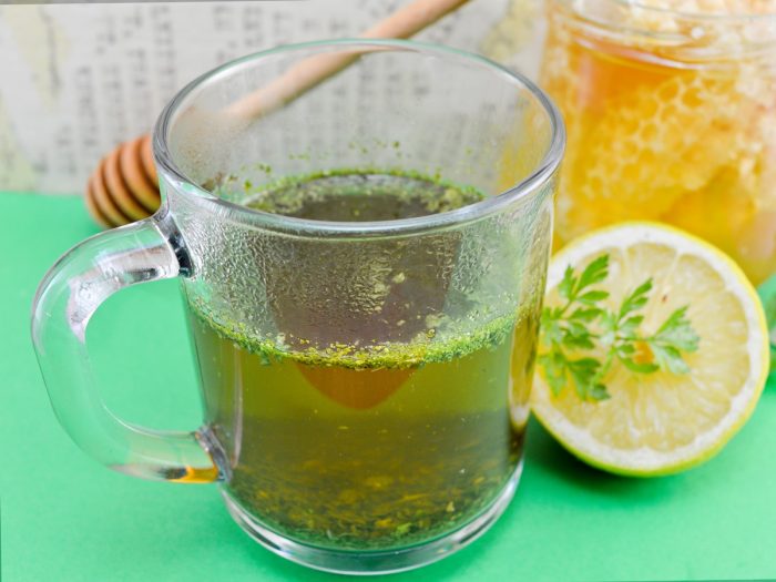 A cup of tea with halved lemon on a green table