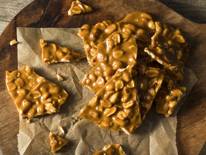 Peanut brittle pieces on a parchment paper placed on a wooden board