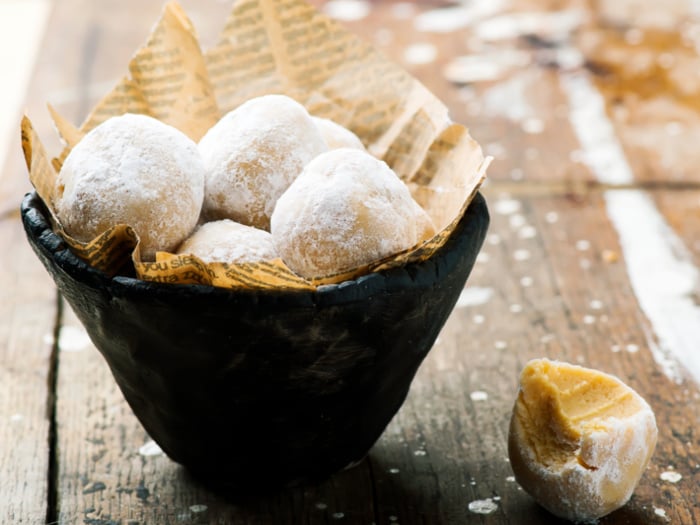 Peanut butter balls rolled in powdered sugar place in a bowl