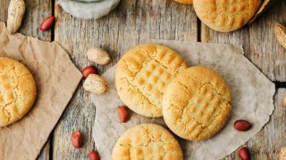 Peanut butter cookies on butter paper with fresh peanut lying around them