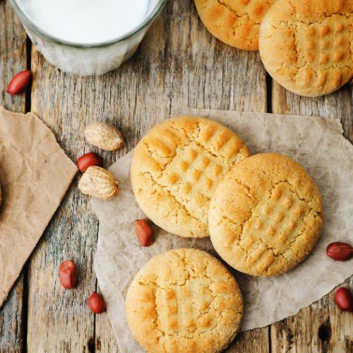 Peanut butter cookies on butter paper with fresh peanut lying around them