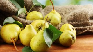 A sack of fresh and ripe green pears on a wooden table