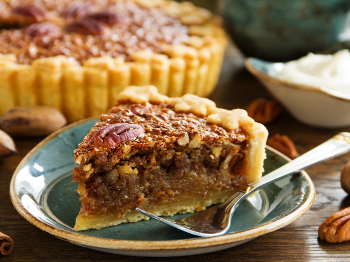 A slice of pecan pie in a dessert plate with fork
