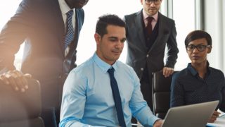 Four people in an office looking into a laptop