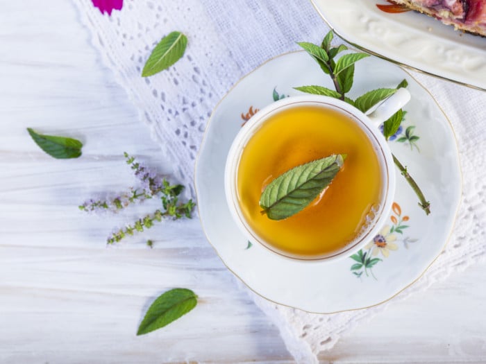 Mint leaves and tea in the cup on a white wooden table